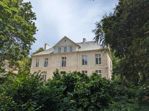 Bény-sur-MerHôtel 4 étoiles Château - Domaine de Coeurmandie的一座大石头房子前面有树木