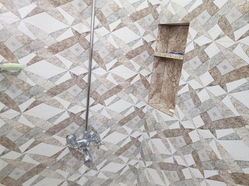 a shower in a bathroom with a tiled wall at Roof Top Resort in Murree