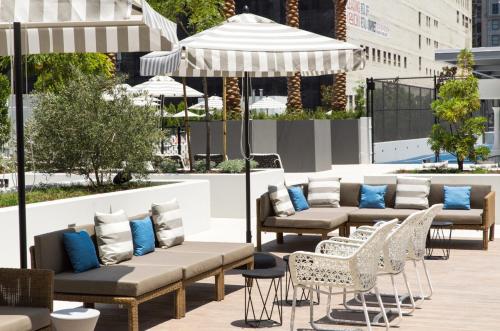 eine Terrasse mit Sofas, Stühlen und einem Sonnenschirm in der Unterkunft Level Los Angeles - Downtown South Olive in Los Angeles