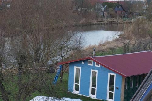 a small house with a red roof next to a river at Gästewohnung von J&O am Fluss. in Jork