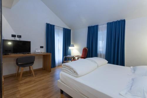 ein Hotelzimmer mit einem Bett und einem Schreibtisch in der Unterkunft Hotel Berthod in Courmayeur