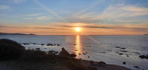 een zonsondergang boven de oceaan met zonsondergang bij Villa au cœur du maquis in Figari