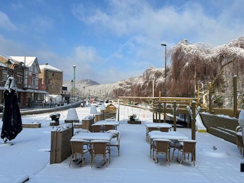 grupa stołów i krzeseł pokrytych śniegiem w obiekcie Hotel Val De La Cascade w mieście Stavelot