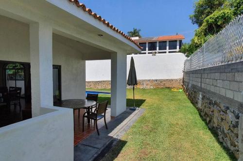 a patio of a house with a table and an umbrella at Casa en lomas de Cocoyoc in Texcalpan