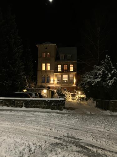 卡塞尔Hotel Burgfeld的夜晚雪中灯火通明的房子