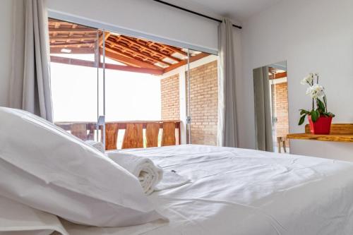 uma cama branca num quarto com uma grande janela em Rancho da Cachaça Pousada em Holambra