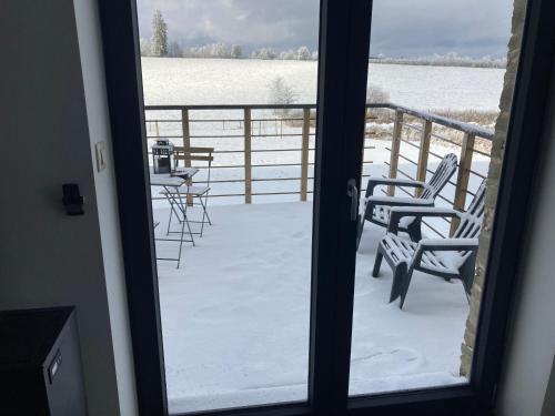 balcone con sedie e tavoli nella neve di Au p'tit cachot (Gîte insolite) a Vaux-sur-Sûre