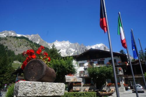 ein Gebäude mit Flaggen davor mit Bergen in der Unterkunft Hotel Aiguille Noire in Courmayeur