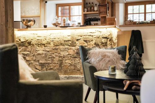 Cette chambre est dotée de chaises, d'une table et d'un mur en pierre. dans l'établissement Hôtel Restaurant La Ferme de Cupelin, à Saint-Gervais-les-Bains