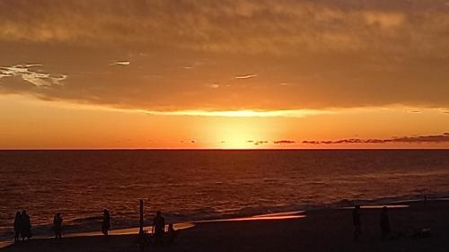 een groep mensen die bij zonsondergang op een strand staan bij Agua Corazones in San Luis