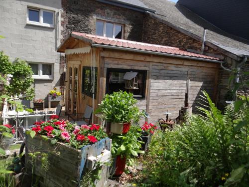 a wooden shed with flowers in front of a house at B&B Le bruissement in Bièvre