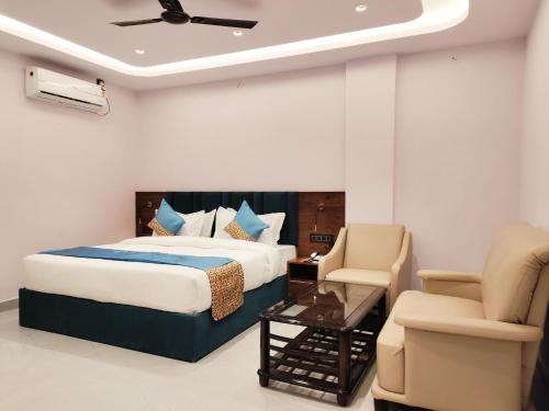 a bedroom with a bed and a chair and a table at Emerald Suites in Greater Noida