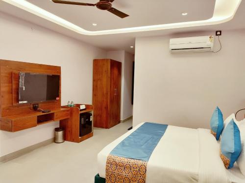 a bedroom with a bed and a flat screen tv at Emerald Suites in Greater Noida