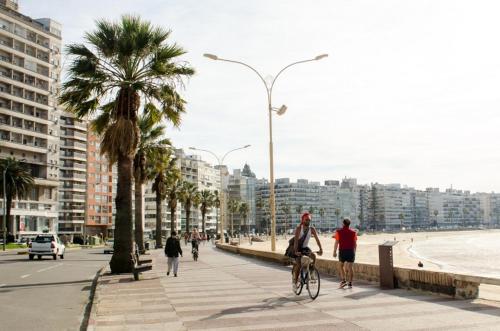 un gruppo di persone che vanno in bicicletta su un marciapiede vicino alla spiaggia di 27 Suites Hotel a Montevideo