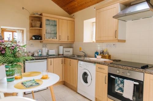 cocina con armarios de madera y lavavajillas blanco en Kitts Cottage Redruth, en Redruth