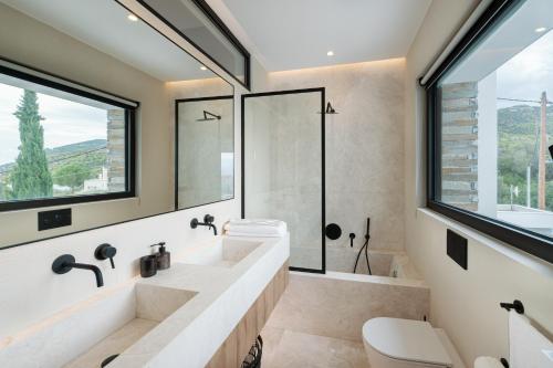 a bathroom with two sinks and a shower and a window at Elia Cove Luxury Villa with private Grand Pool in Korinthos