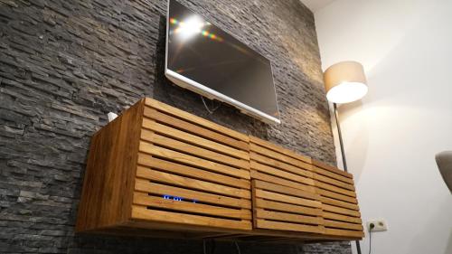 a tv on a brick wall with a wooden dresser at Maison 3 chambres proximité aéroport et grand axes in Charleroi