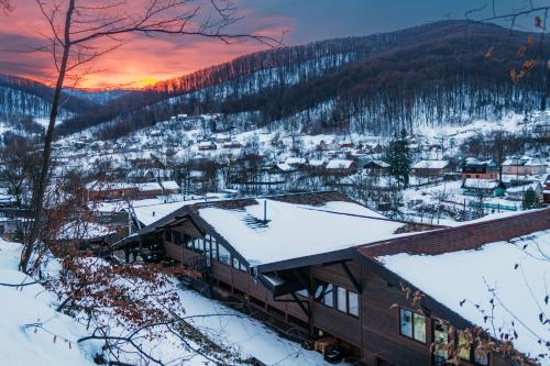 uma casa na neve com o pôr-do-sol ao fundo em BRB Park Hotel em Vizhenka