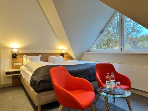 una camera con un letto e due sedie rosse di Hotel Stempferhof a Gössweinstein