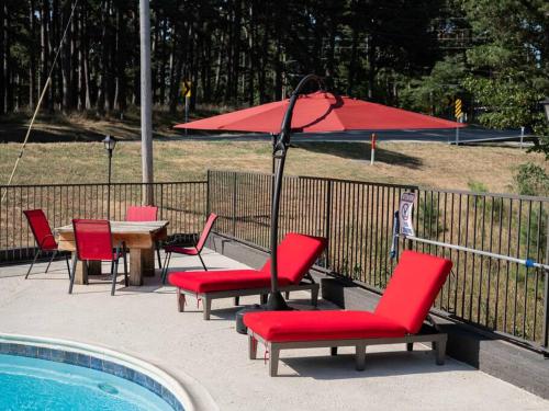 a table and chairs with an umbrella next to a pool at Stonegate Lodge King Bed WIFI 50 Roku TV Salt Water Pool Room #104 in Eureka Springs