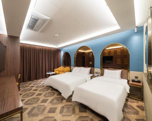 a hotel room with two beds and a blue wall at Hotel Mayotte in Uiwang