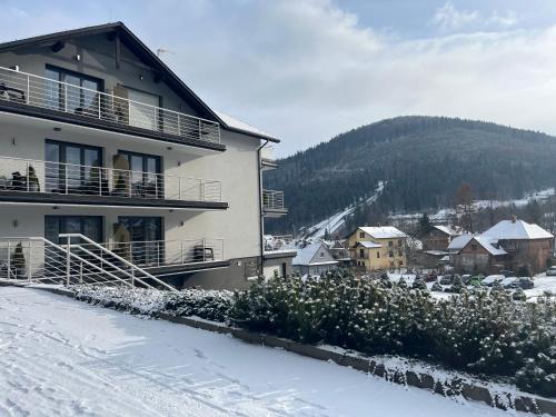 un edificio con nieve en el suelo en una ciudad en Apartamenty Sun, en Szczyrk