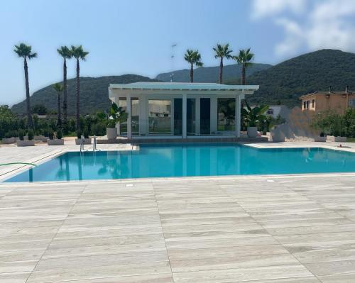 a swimming pool with a house and palm trees at Female Resort in San Felice Circeo