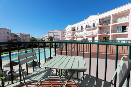 een balkon met een tafel en stoelen naast een zwembad bij B95 - Casa Melo Apartment in Praia da Luz in Luz