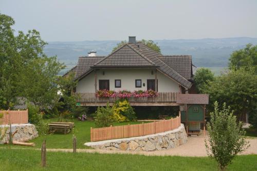 une maison avec une terrasse couverte et une clôture devant elle dans l'établissement Bio-Bauernhof Haunschmid, à Ardagger Markt