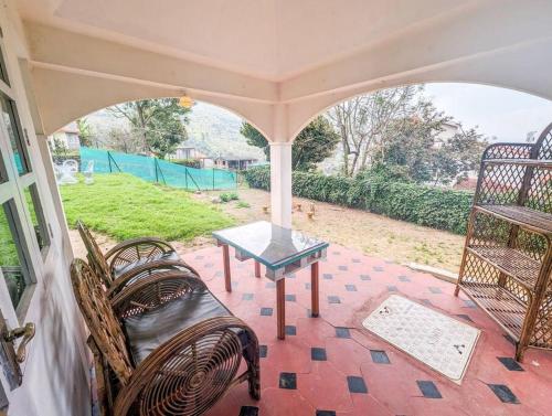 een veranda met 2 stoelen en een tafel. bij Bohemian Hideaway - Vintage Vibe 3BHK Villa in Kodaikānāl