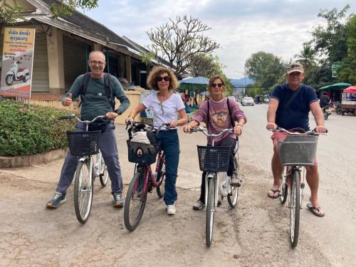 um grupo de pessoas andando de bicicleta por uma rua em Villa Chitchareune 2 em Luang Prabang