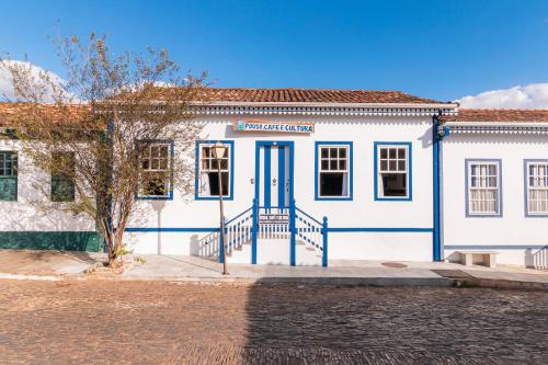 ein weißes Gebäude mit blauer Tür auf einer Straße in der Unterkunft Pouso, Café e Cultura in Pirenópolis