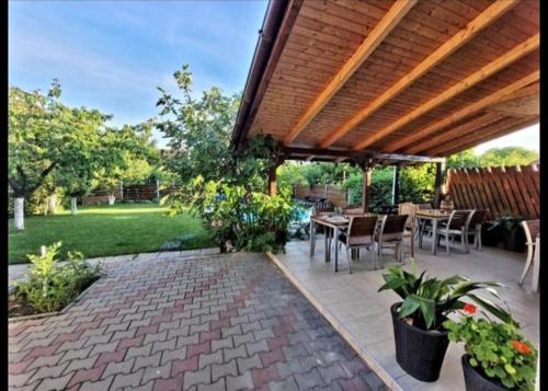 eine Terrasse mit einem Tisch und Stühlen unter einer hölzernen Pergola in der Unterkunft LA CASSA in Timişoara