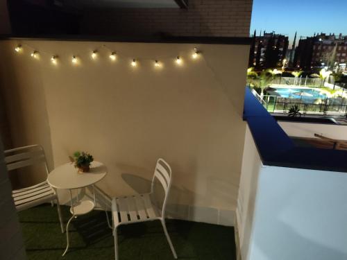 a small table and chairs on a balcony with lights at Apartamento Servet, parking gratuito in Bormujos