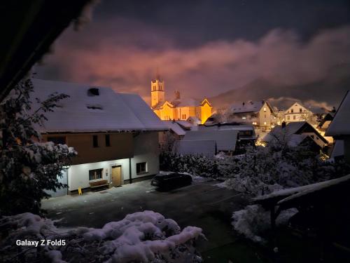 Una ciudad iluminada por la noche con una iglesia en Tourist farm Megušar, en Škofja Loka