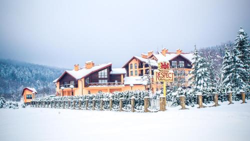 a house covered in snow with a sign in front at СПА-Готель "RESPECT" in Skhidnitsa