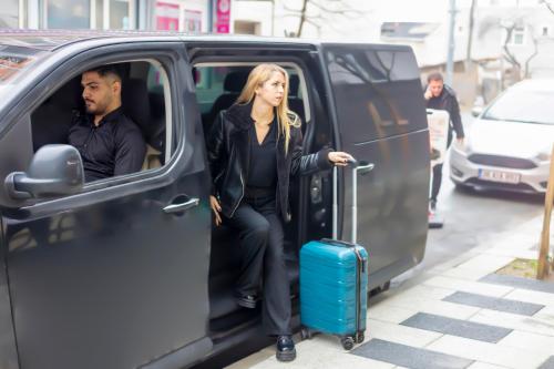 a woman is getting out of a van with a suitcase at Dem Premium Hotel - Round Trip Airport Service - Istanbul International Airport in Arnavutköy