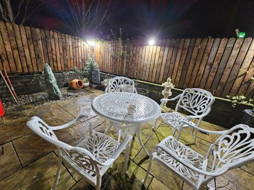 - une table et des chaises blanches sur la terrasse la nuit dans l'établissement Central Westport Town House, à Westport