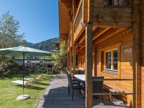 una terraza de madera con mesa y sombrilla en Waldberg, en Krimml