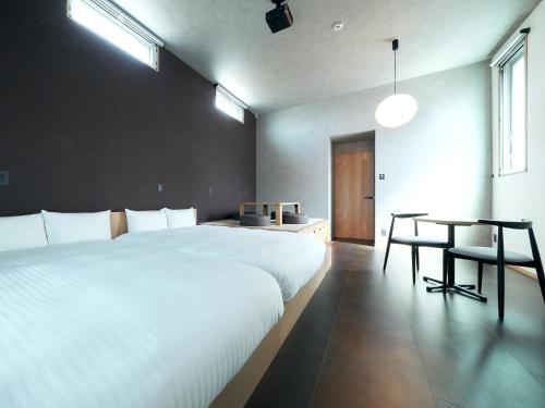 een slaapkamer met 2 witte bedden en een tafel bij Rakuten STAY Hakata Gion 101 Superior Room in Fukuoka