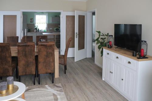 sala de estar con mesa de comedor y TV en Apartment Am Mittelpunkt Deutschlands, en Niederdorla