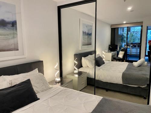 una camera con due letti e uno specchio di Midnight Luxe 1BR 1Bath Apartment 104 in the heart of Braddon Pool Sauna Secure Parking Wine WiFi a Canberra