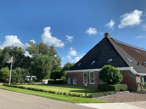 een rood bakstenen huis met een zwart dak bij Bed and Breakfast de Salix in Hitzum