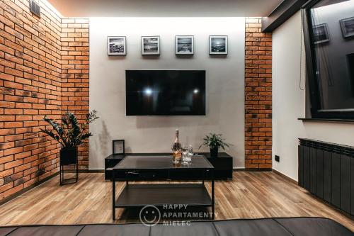 a living room with a flat screen tv on a brick wall at Happy Night - ApartamentyHappy pl in Mielec