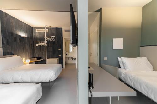 a hotel room with two beds and a mirror at Open Hotel in Rimini