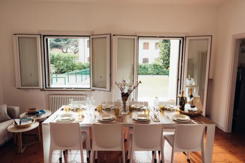 a dining room with a table and chairs and windows at Anima Jesolo - Ca' delle Rose in Lido di Jesolo