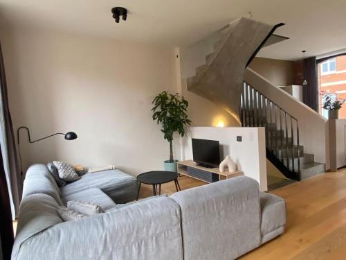 a living room with a couch and a staircase at Woning Oostende - Oosteroever in Ostend