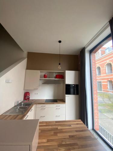 a kitchen with white cabinets and a large window at Woning Oostende - Oosteroever in Ostend