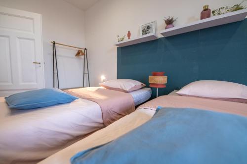 Cette chambre comprend 2 lits et un mur bleu. dans l'établissement Plumeria - Grand Appartement 75m2 - Au calme - Proche Gare, Nouvelle Ville - Parking Public Gratuit - 2 Chambres - 4 Lits séparés, à Metz