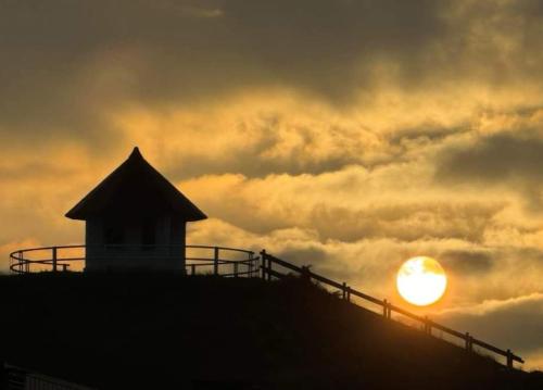 una silueta de un edificio con la puesta de sol en el fondo en Appartement Studio Wenduine, en De Haan